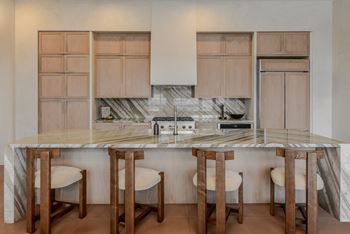 A kitchen with a marble countertop and wooden bar stools.